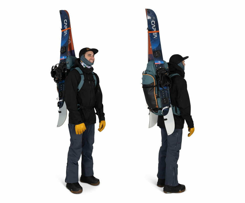 The image features a person wearing winter gear, suitable for snowboarding or skiing. They are dressed in a black jacket and dark pants with yellow gloves, suggesting they are equipped for cold weather. The individual has a snowboard strapped vertically t