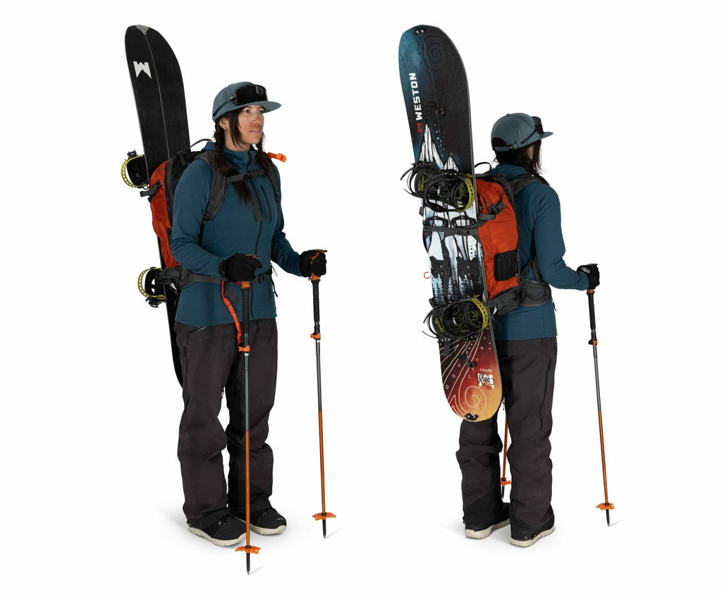 The image features a person dressed in winter outdoor gear, equipped for a snowboarding excursion. They are wearing a teal jacket, dark pants, and sturdy black boots. The person is carrying a large orange backpack to which a snowboard is securely attached