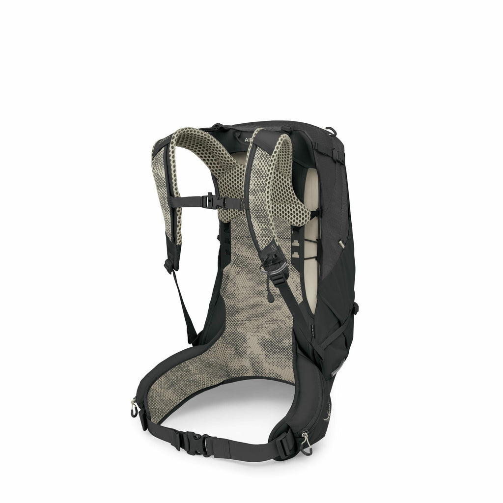 The image depicts a black backpack with a focus on its back and straps, showcasing its ergonomic design. The backpack features a mesh padding system, likely intended to enhance breathability and comfort during wear. Straps and adjustable buckles can be se