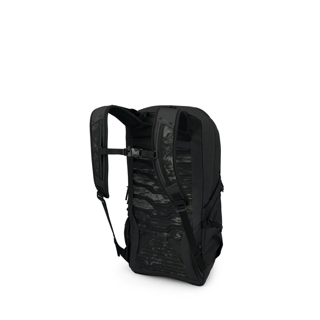 The image shows a black backpack photographed from the back-left angle. It has padded shoulder straps with an adjustable sternum strap and a ventilated mesh back panel featuring wavy cutouts. The pack has a streamlined, rectangular shape with side compres