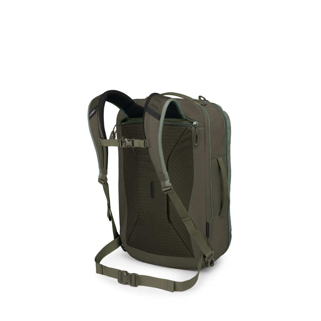 A green travel backpack is shown from a rear three-quarter view on a white background. It features padded shoulder straps, a sternum strap, and a hip belt for stability. The back panel is ventilated mesh, and there's a zippered pocket near the top with ad