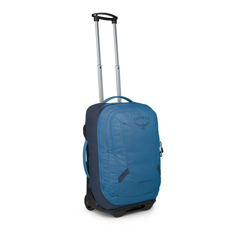 The images show a compact rolling travel bag in blue with a subtle grid pattern. It features a telescoping handle, two wheels, and multiple grab handles on the top and side for easy carrying. The front has a zippered pocket with small reflective tabs and