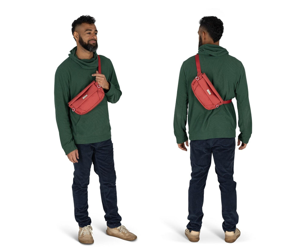 The image shows a man standing in a studio setting, captured from two angles: front and back. He is wearing a dark green hoodie paired with dark blue jeans and light brown sneakers. Across his body, he has a red crossbody bag, which hangs from his left sh
