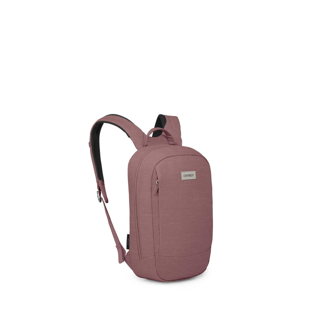 The image features an Osprey backpack in a muted pink color. This sleek and modern backpack has a streamlined design with a single main compartment and a smaller front pocket, both equipped with zippers. The Osprey logo is prominently displayed on a fabri