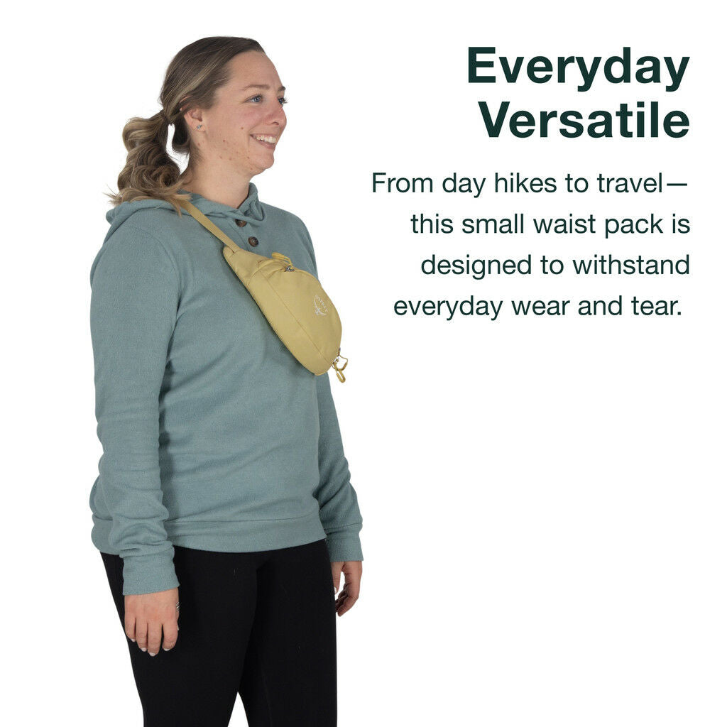 Woman wearing a teal sweatshirt and black leggings with a small, light-yellow Osprey waist pack.