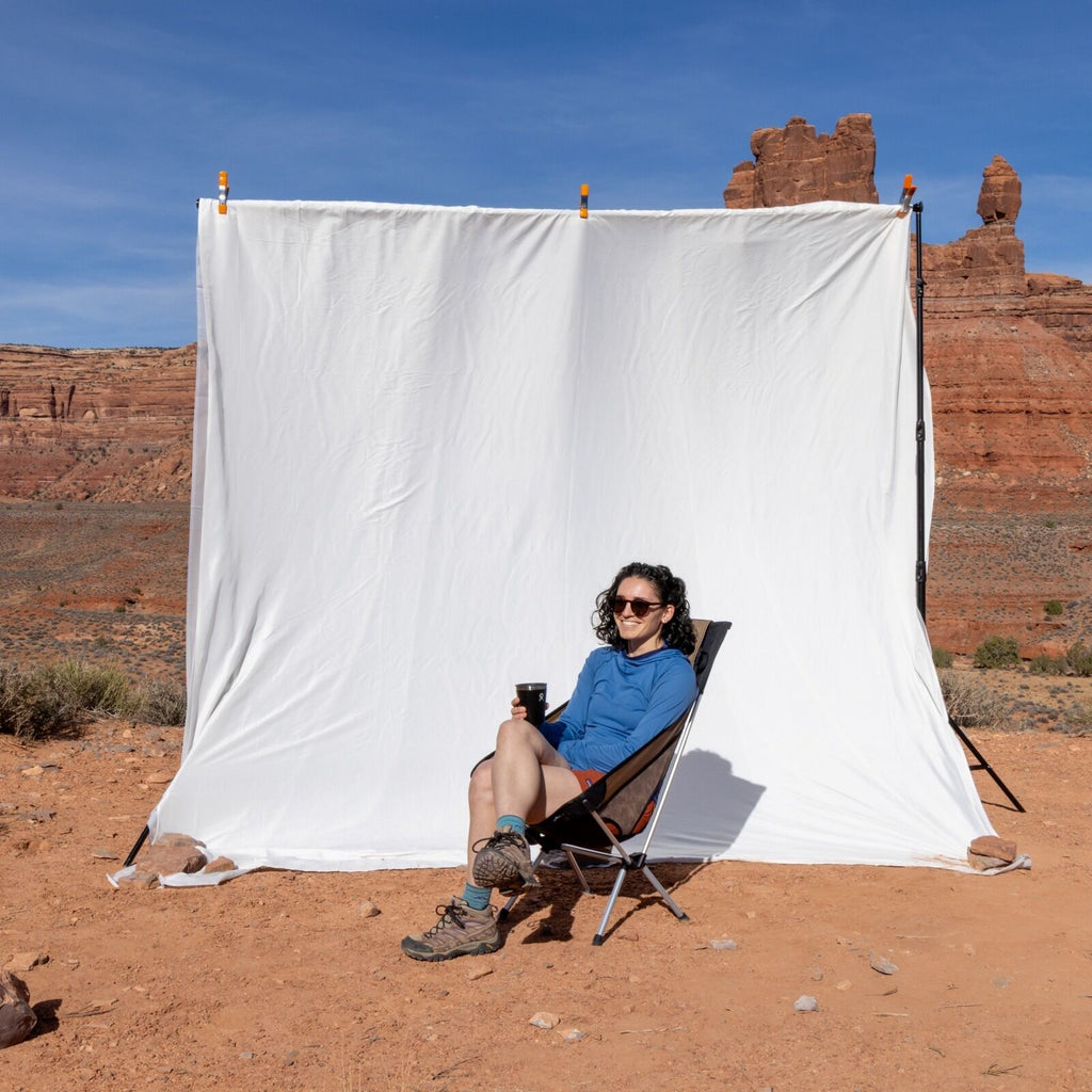 Image of model sitting in the Helinox Campcore Chair One High-Back (re) in the desert