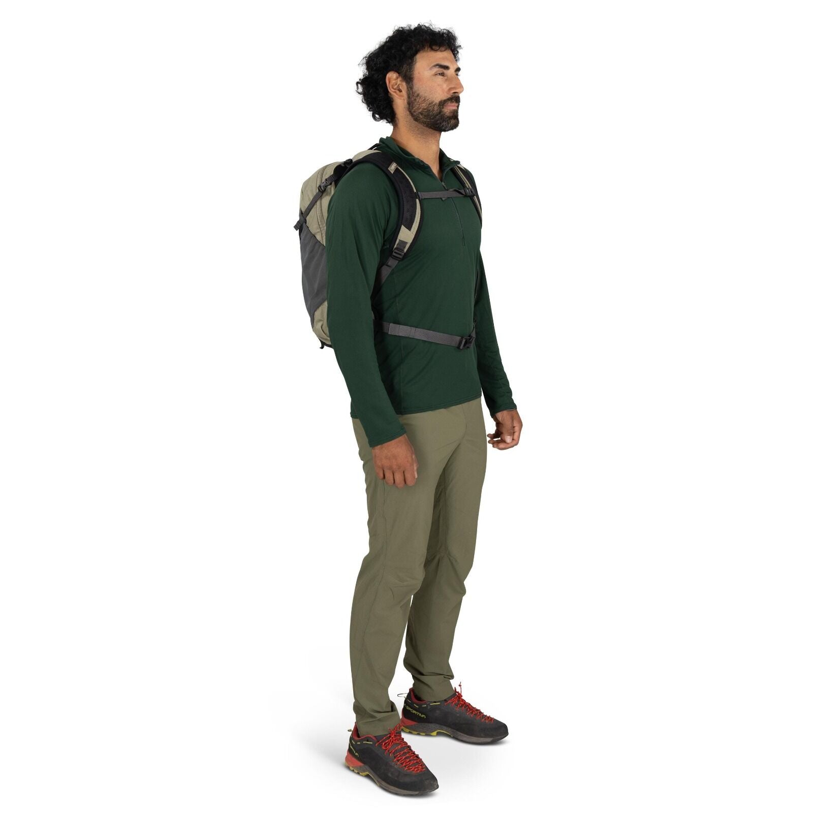 The image shows a person dressed in outdoor hiking attire. They are wearing a dark green long-sleeve shirt and khaki-colored pants, which appear to be suitable for trekking or hiking activities. The person has on a pair of black hiking shoes with bright r