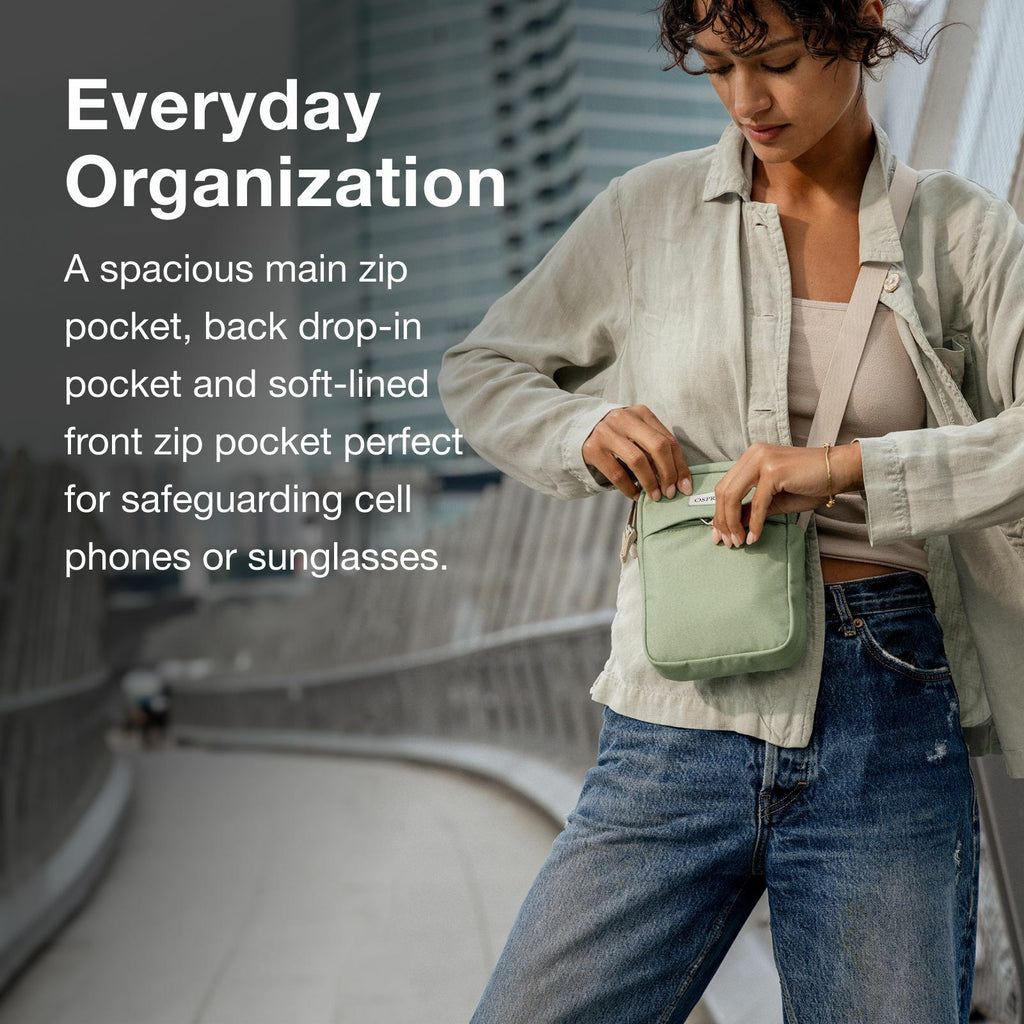 A woman holds a small green pouch while standing on a city path, showcasing its spacious pockets for organizing essentials.