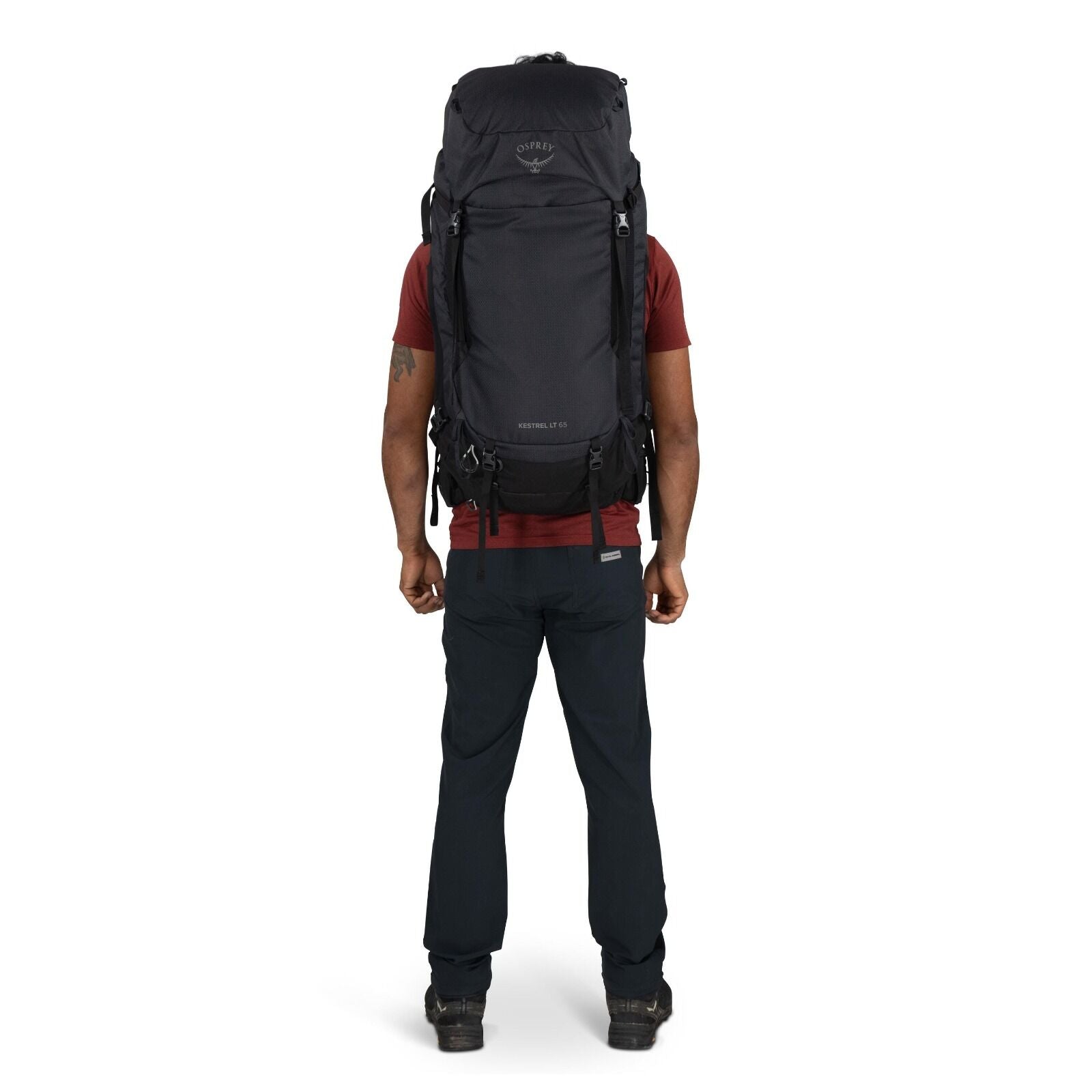 The image features a person standing with their back facing the camera, wearing a large backpack designed for hiking or outdoor adventures. The backpack is black and prominently displays the Osprey logo near the top, with "Kestrel 70" written below it, in