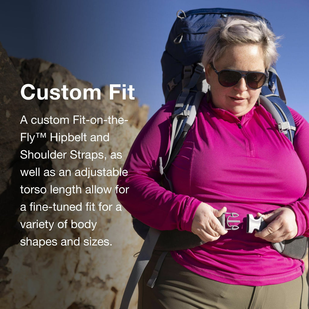 A hiker in a vibrant pink top adjusts their backpack's custom hipbelt and shoulder straps against a rocky landscape.