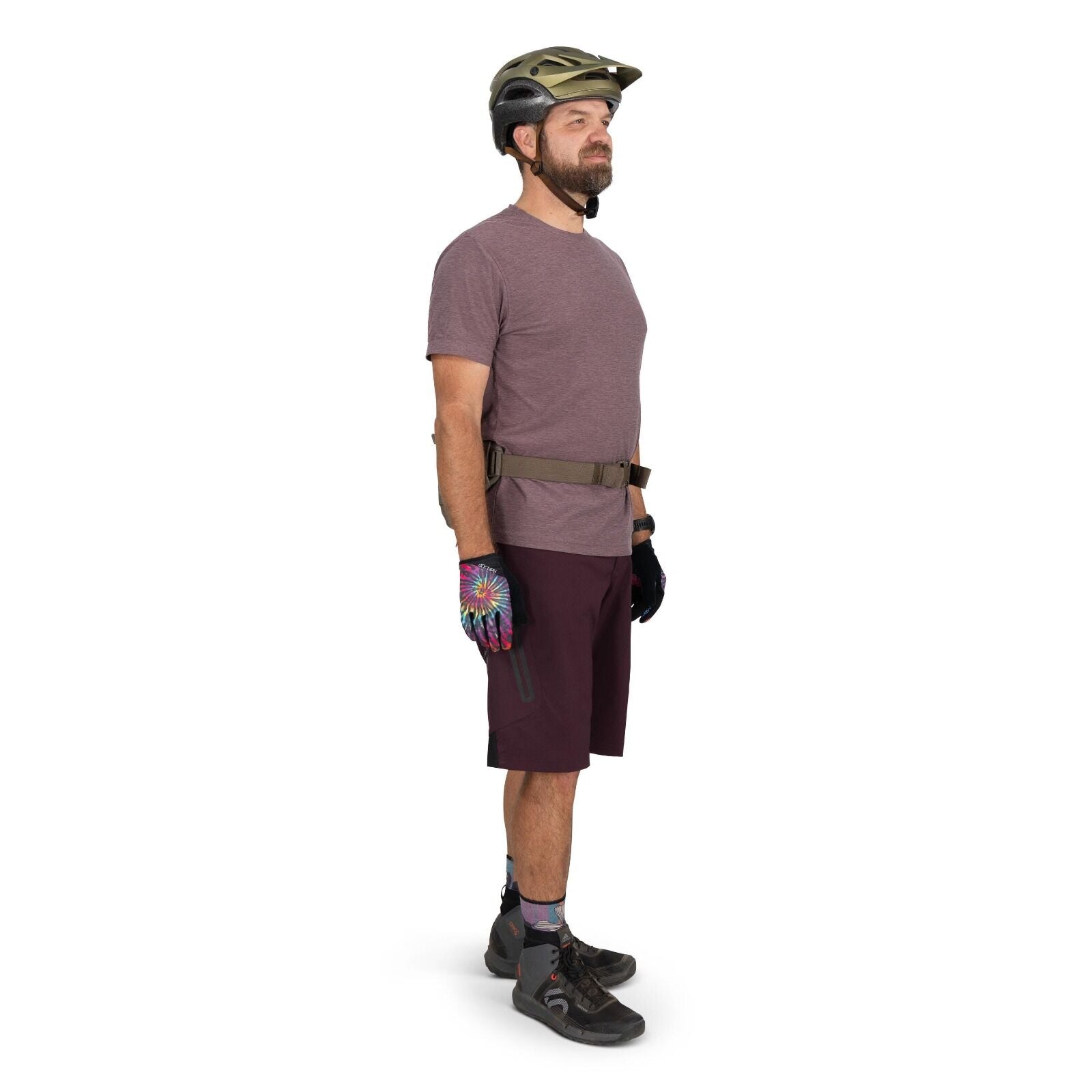 The image features a man standing in a side profile pose, wearing mountain biking gear. He is dressed in a purple short-sleeve shirt paired with matching purple shorts. On his hands, he has vibrant gloves with colorful patterns, adding a touch of flair to