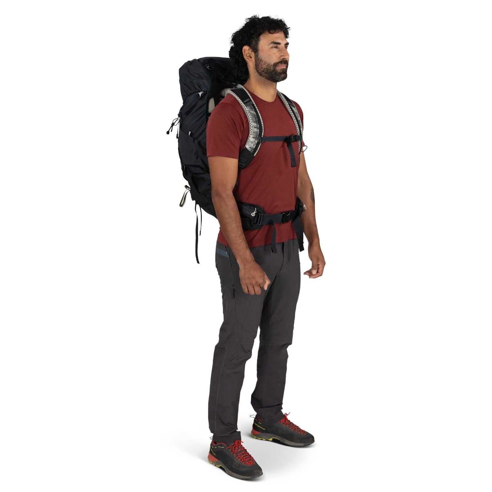 The image features a person standing upright, wearing a hiking outfit suitable for outdoor activities. They are dressed in a red short-sleeved t-shirt and dark gray pants with zipper pockets. On their feet are a pair of black and gray hiking shoes with re