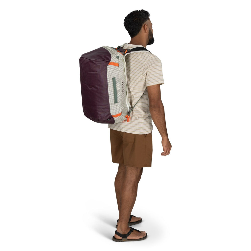 The image features a person standing and wearing a duffel bag.