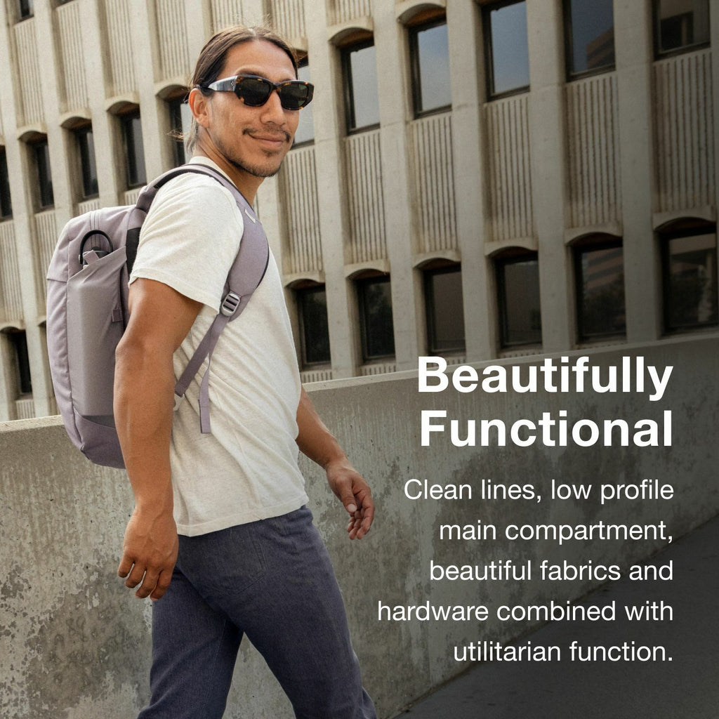 A person walks along a concrete pathway wearing a stylish gray backpack, highlighting its sleek design and practical features.