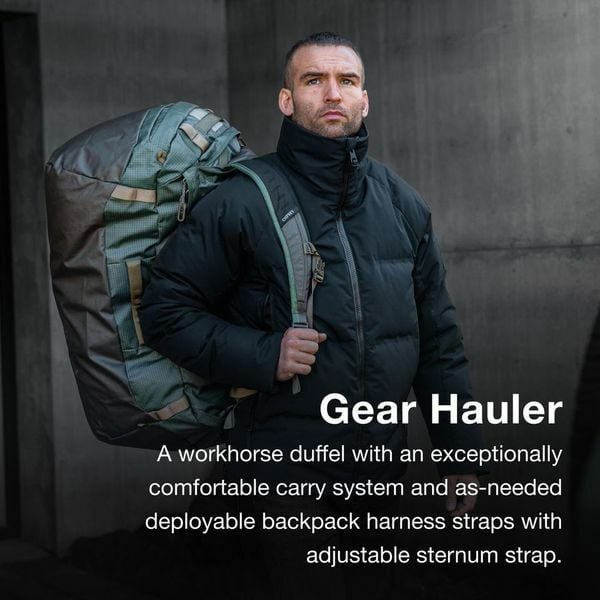 Man carrying a large, green and brown duffel bag with backpack straps. Gear Hauler.