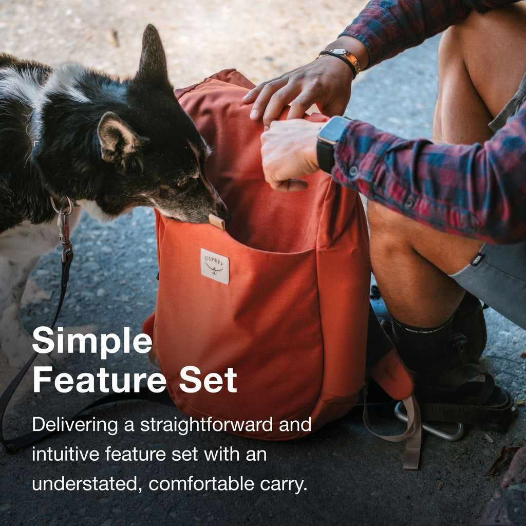 A person crouches next to a brown dog, interacting with a red backpack labeled "OSPREY," emphasizing simple, intuitive design.